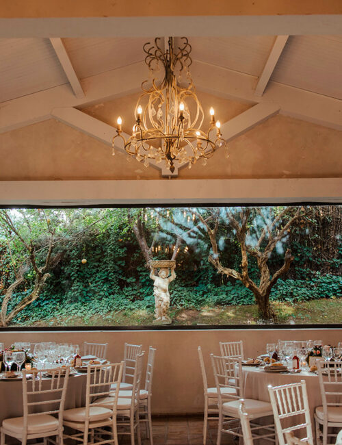 Amplio y luminoso salón comedor con grandes ventanales y mesas colocadas para una celebración